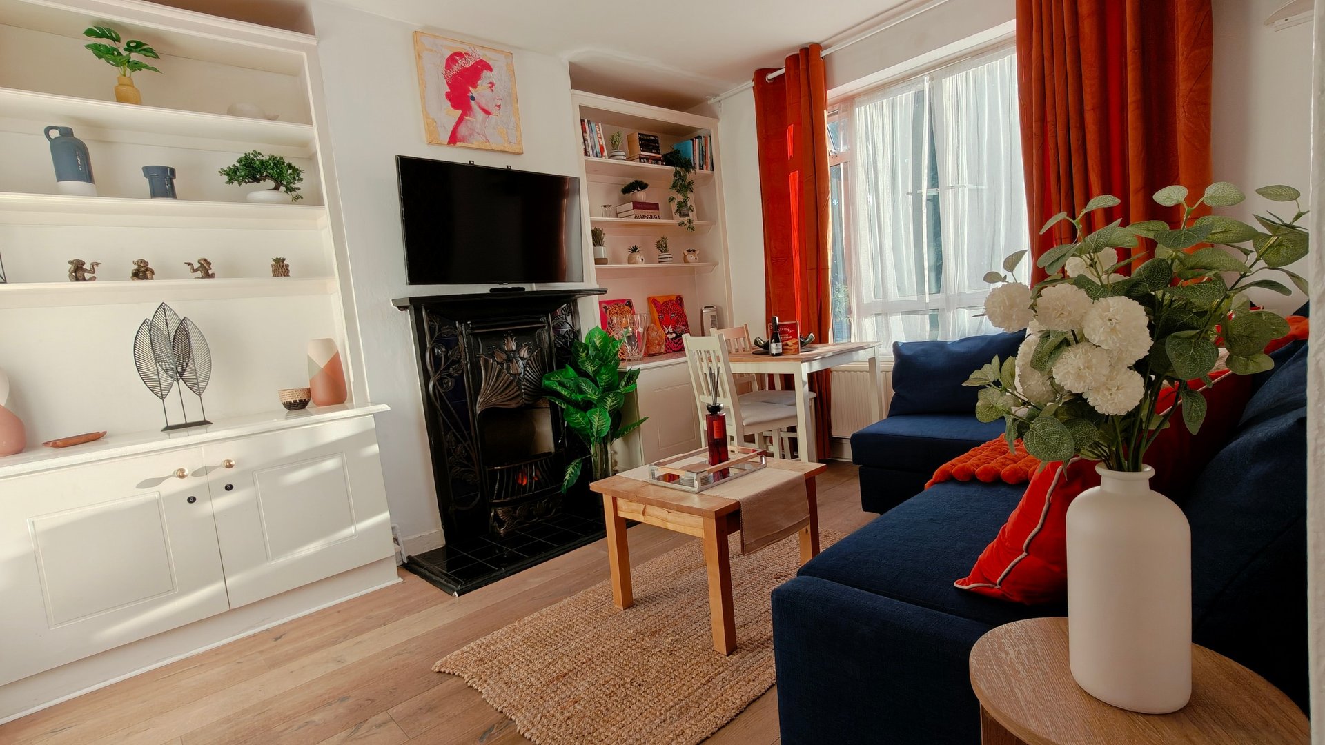 Modern living room with white shelving, fireplace, navy sofa, and red curtains