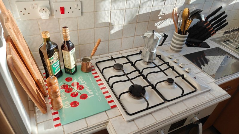 Kitchen counter with gas hob, cooking utensils, bottles, and decorative items