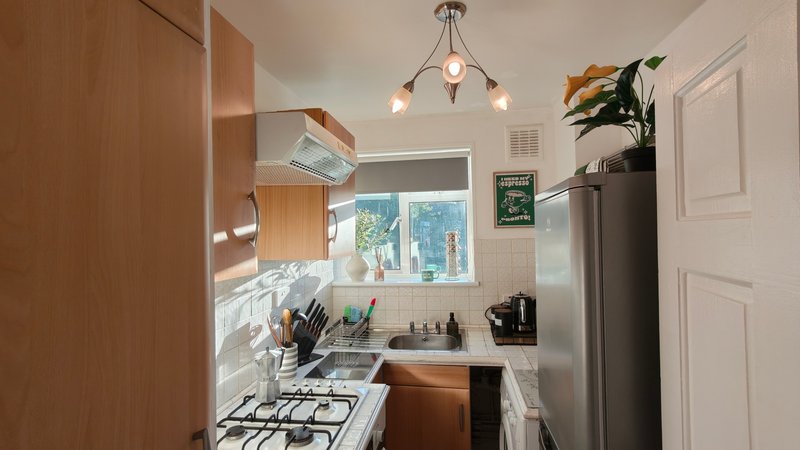 Compact kitchen with wood cabinets, gas hob, stainless steel sink and pendant lighting