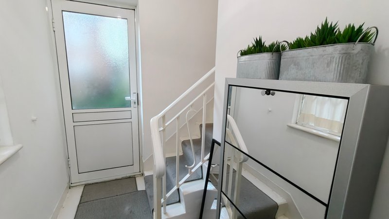 Staircase landing with white door, potted plants, and storage shelving