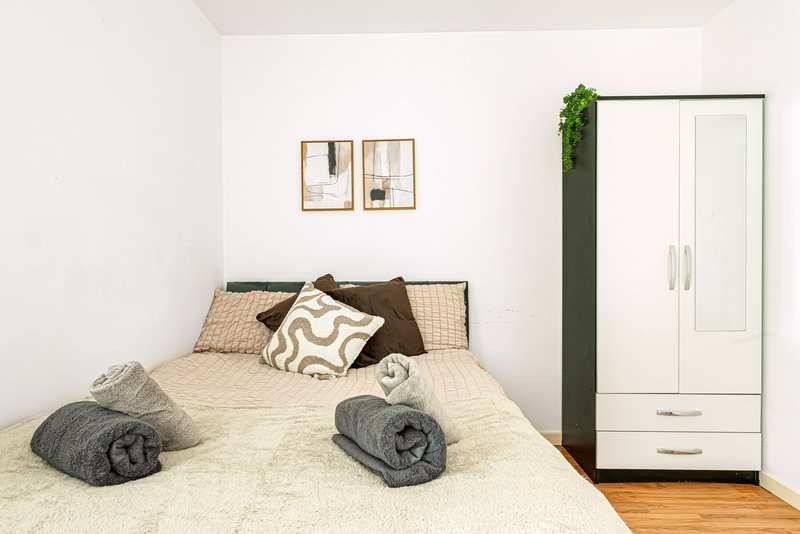 Bedroom with double bed, rolled towels, decorative pillows, wardrobe and wall art