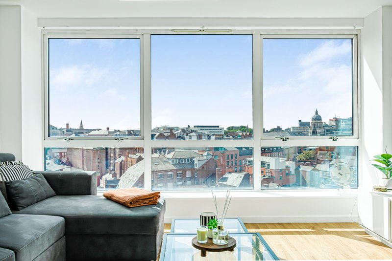 Modern living room with grey sofa, large windows overlooking city skyline and rooftops