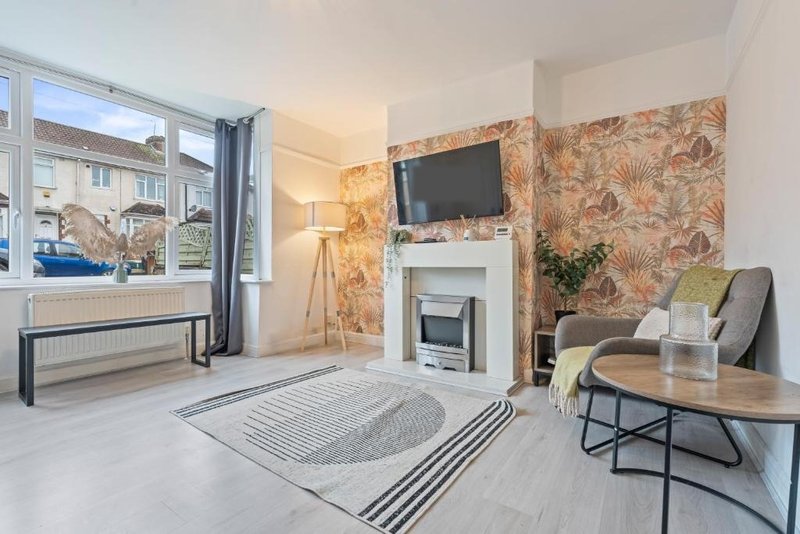 Modern living room with fireplace, TV, wooden coffee table and patterned wallpaper