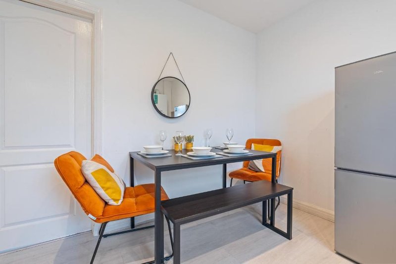 Modern dining area with orange chairs, black table, bench seating and round mirror