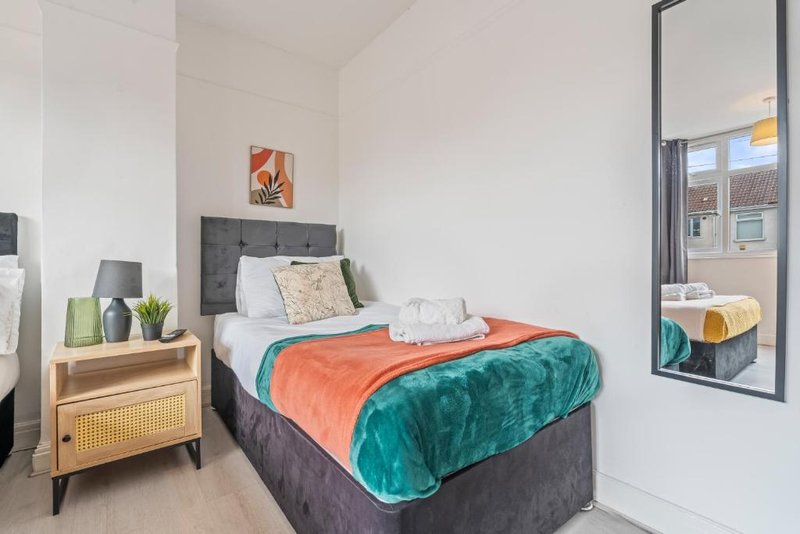 Bedroom with double bed, grey headboard, wooden nightstand and mirror reflecting street view