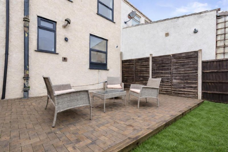 Patio area with garden furniture, wooden fence panels, and manicured lawn