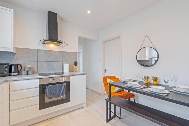 Modern kitchen and dining area with white cabinetry, black appliances, and round mirror on wall