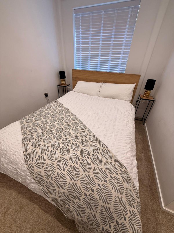 Bedroom with double bed, wooden headboard, white shutters and bedside tables with lamps