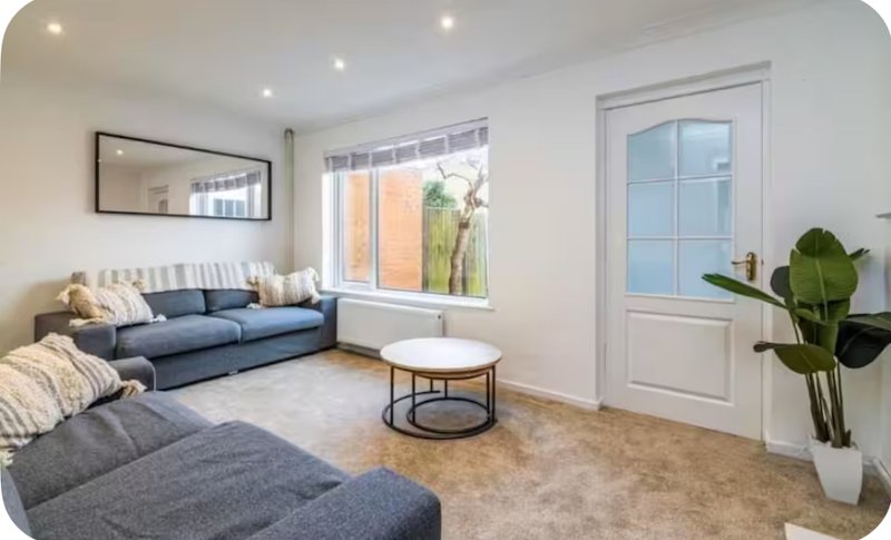 Bright living room with blue sofa, gray armchair, round coffee table and potted plant