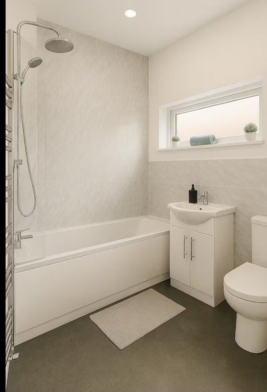 Clean modern bathroom with white bathtub, shower enclosure, vanity sink and toilet
