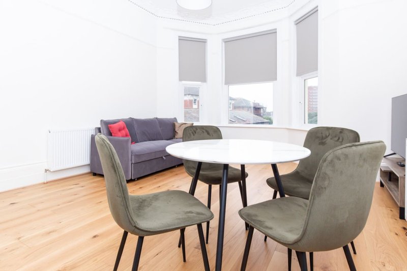Modern living room with round white table, grey chairs, purple sofa and bay windows