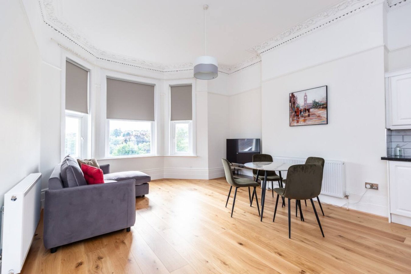 Bright living room with grey sofa, dining table, bay windows and wooden flooring