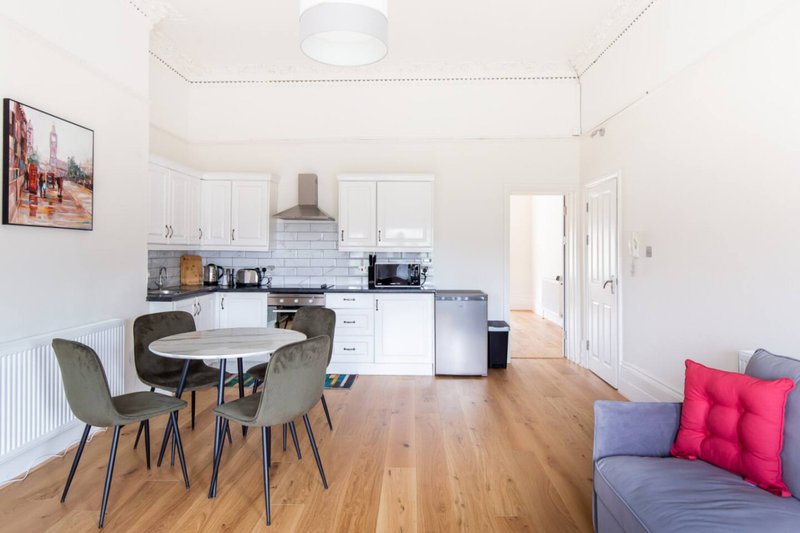 Open-plan kitchen and dining area with white cabinetry, dining table, chairs, and living room seating
