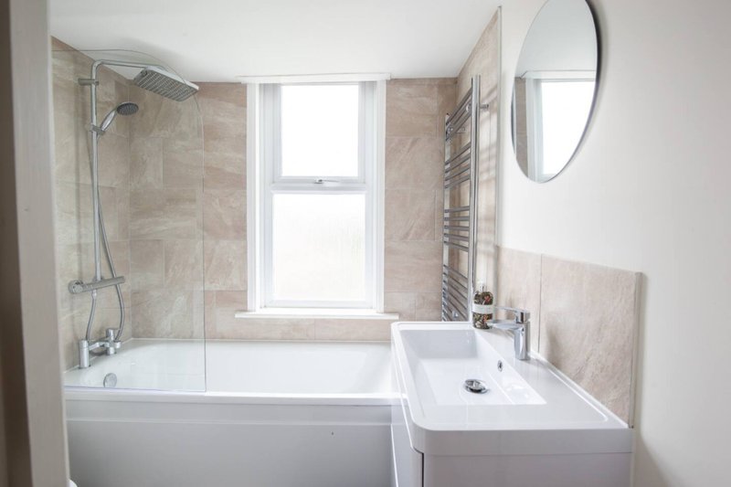Modern bathroom with bathtub, shower enclosure, sink and oval mirror