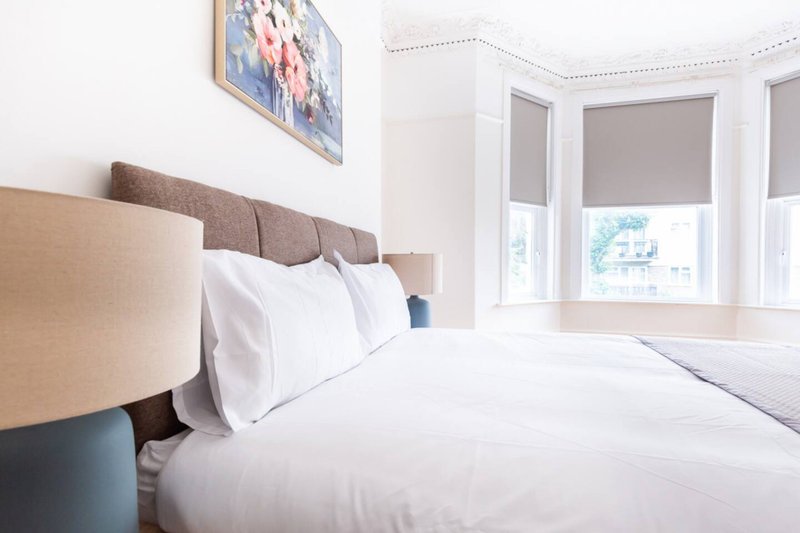Bright bedroom with double bed, beige headboard, white bedding and wall art