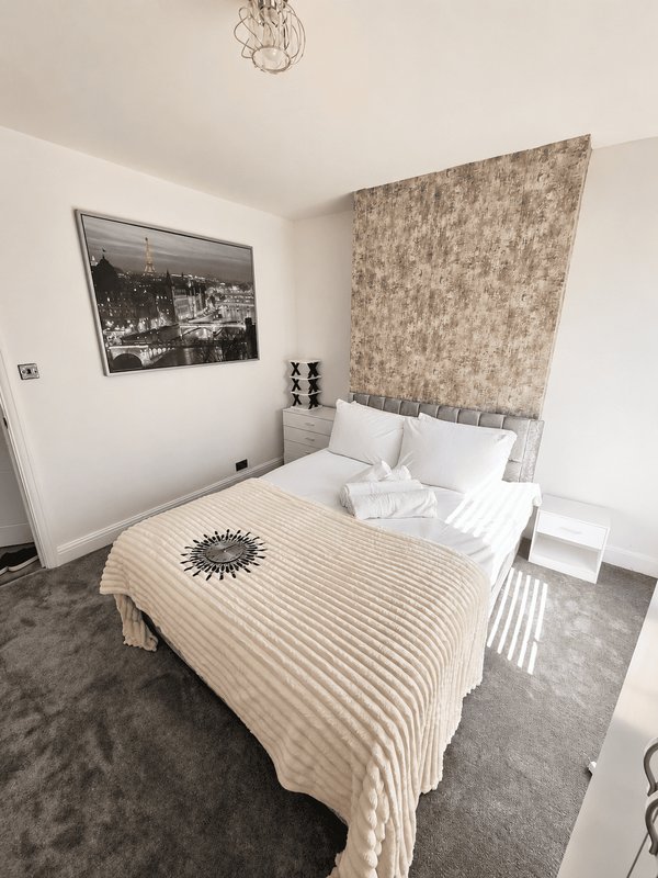 Bedroom with double bed, striped bedding, patterned headboard and framed wall art