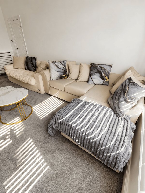 Bright living room with cream sectional sofa, striped blanket, decorative pillows and round side table