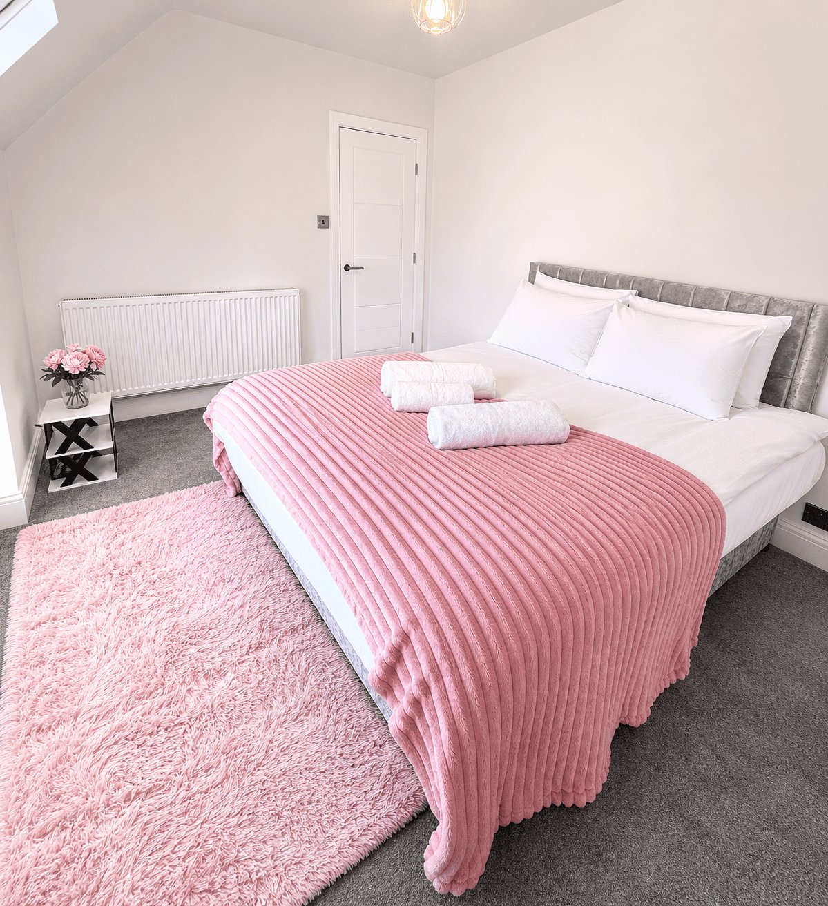 Bright bedroom with pink striped bedding, white pillows, pink rug and radiator