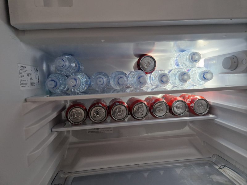 Refrigerator interior with bottled beverages and jars arranged on shelves
