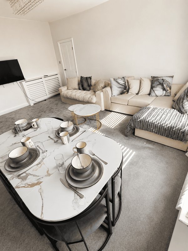 Open-plan living space with dining table, beige sofa, striped bed, and natural light