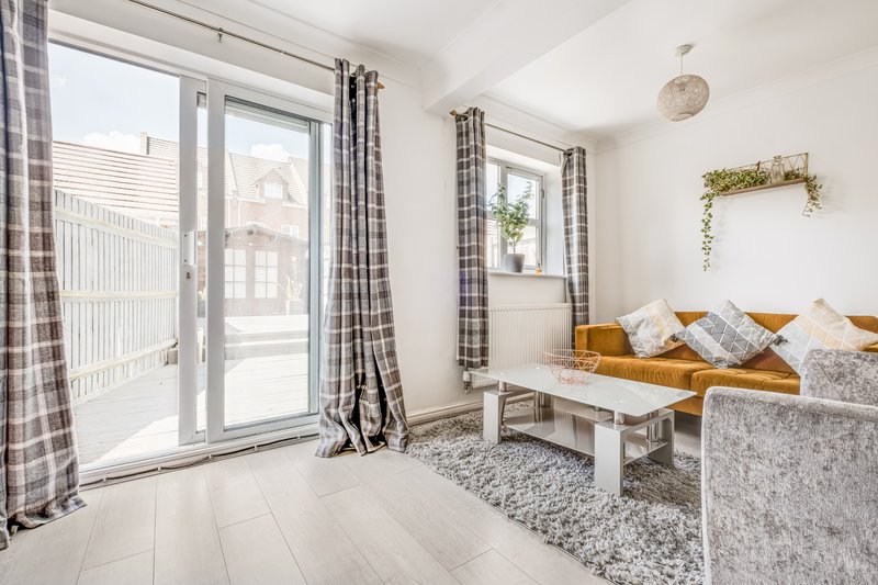 Bright living room with sofa, white wooden floor, large windows and gingham curtains