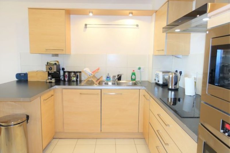 Modern kitchen with light wood cabinets, stainless steel appliances and dark countertops