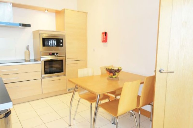 Modern kitchen with wooden cabinets, built-in oven, and dining table with chairs