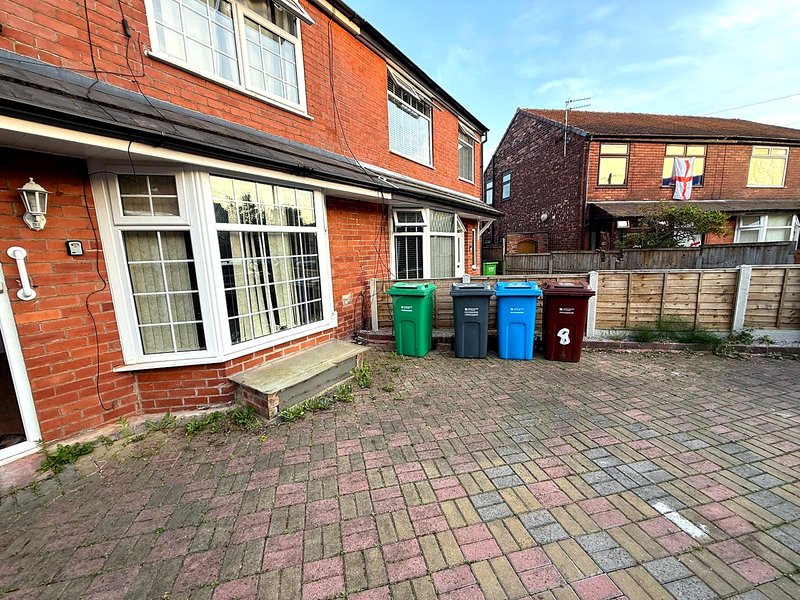 Red brick semi-detached house exterior with patio, patio doors, and waste bins