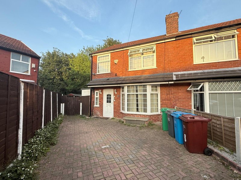 Red brick semi-detached house with driveway, garage, and colorful waste bins