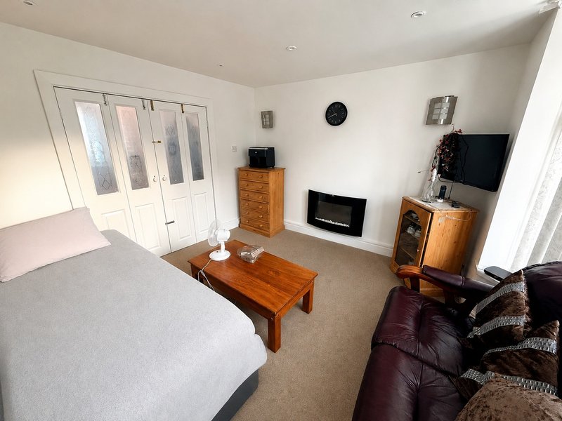 Spacious bedroom with bed, wooden furniture, fireplace, TV, and seating area