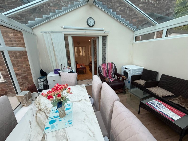 Modern conservatory with marble dining table, pink sofa, flowers and skylight windows