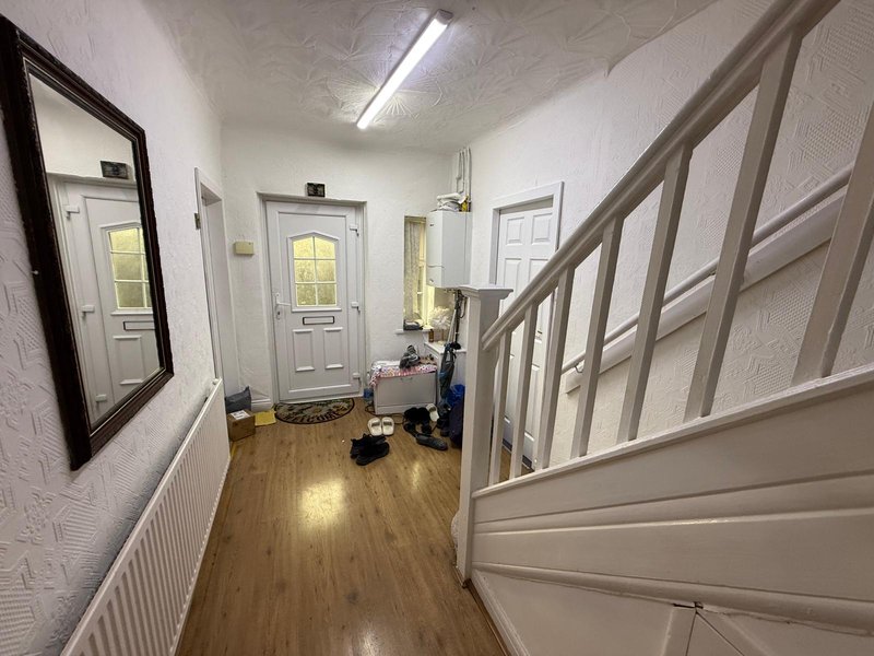 Hallway with wooden floor, white walls, staircase, mirror and multiple doors