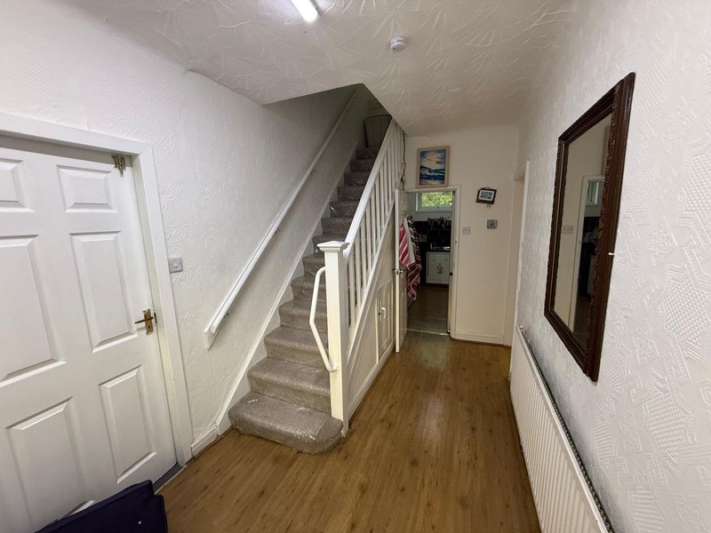 Hallway with staircase, white walls, wooden floor and framed wall art