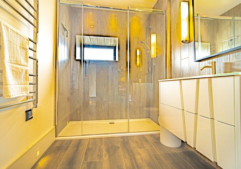 Modern bathroom with walk-in shower enclosure, heated towel rack, and yellow accent wall