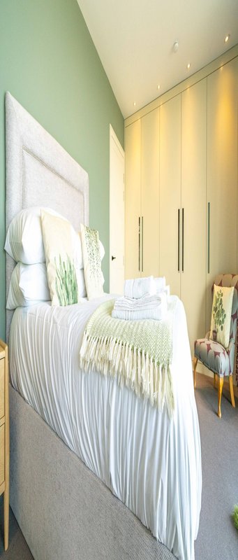 Bedroom with single bed, white bedding, green throw, yellow wardrobe and mint green wall