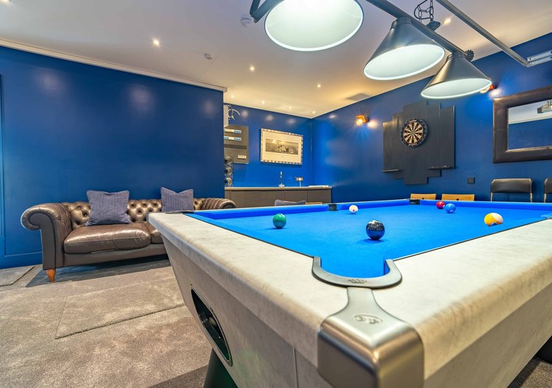 Games room with pool table, blue walls, chesterfield sofa, and overhead lighting