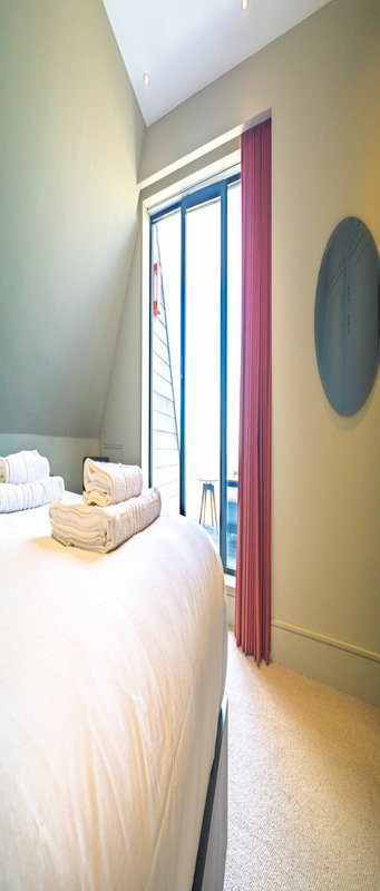Narrow bedroom with single bed, wooden door frame, and circular wall decoration
