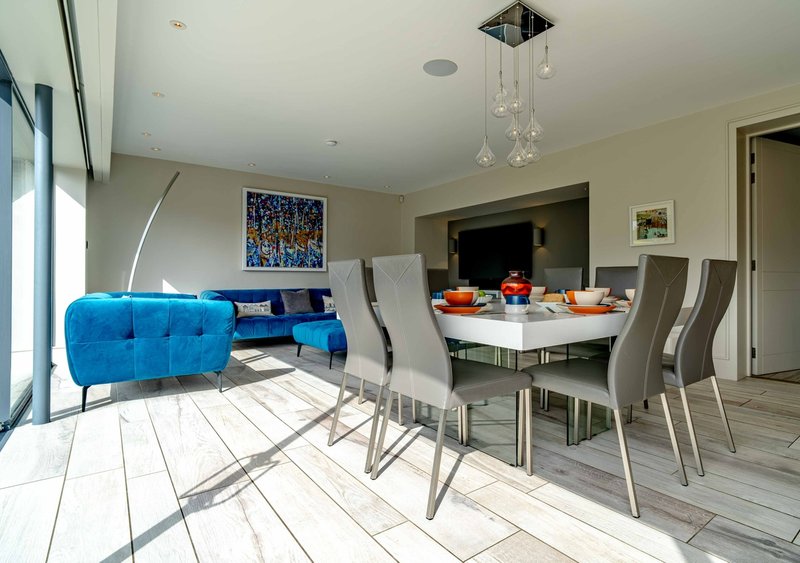 Open-plan living and dining area with blue sofa, dining table, chairs, and pendant lighting