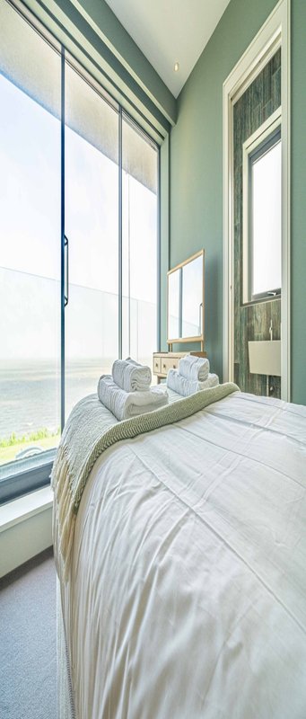 Modern bedroom with bed, large windows, sea view, and minimalist decor