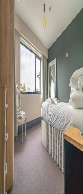 Narrow bedroom with white crib, green walls, wooden door, and window with natural light