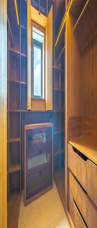 Narrow hallway with built-in wooden cabinetry, blue-framed window, and warm lighting