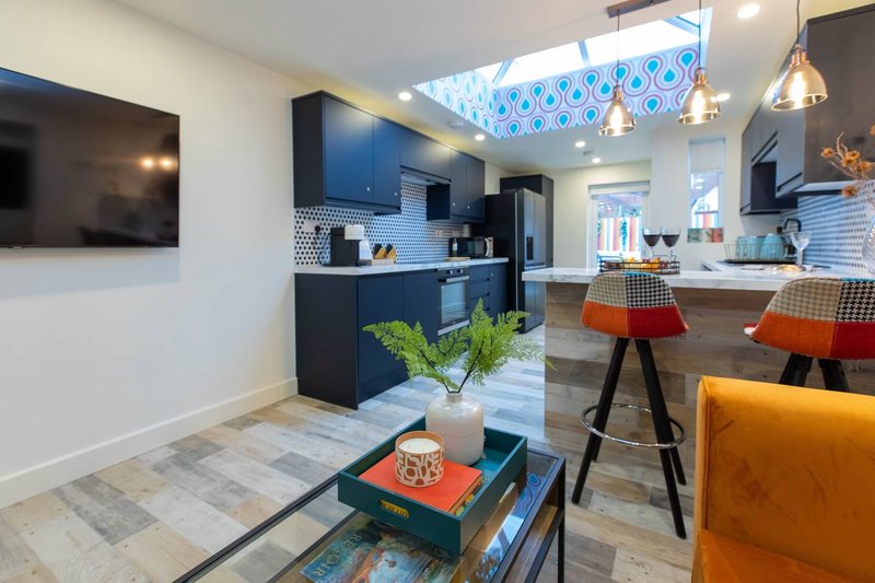 Modern open-plan kitchen and living area with blue cabinetry, island seating, and contemporary furnishings