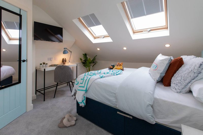 Bright attic bedroom with double bed, desk area, skylight windows and modern furnishings