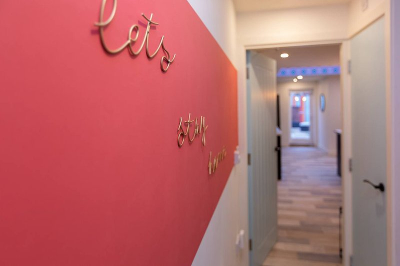 Hallway with pink accent wall featuring decorative gold lettering and white doors