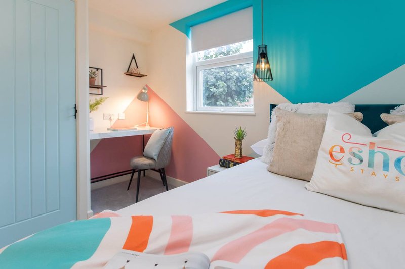 Bright modern bedroom with turquoise and white decor, twin beds, colorful bedding, and window view