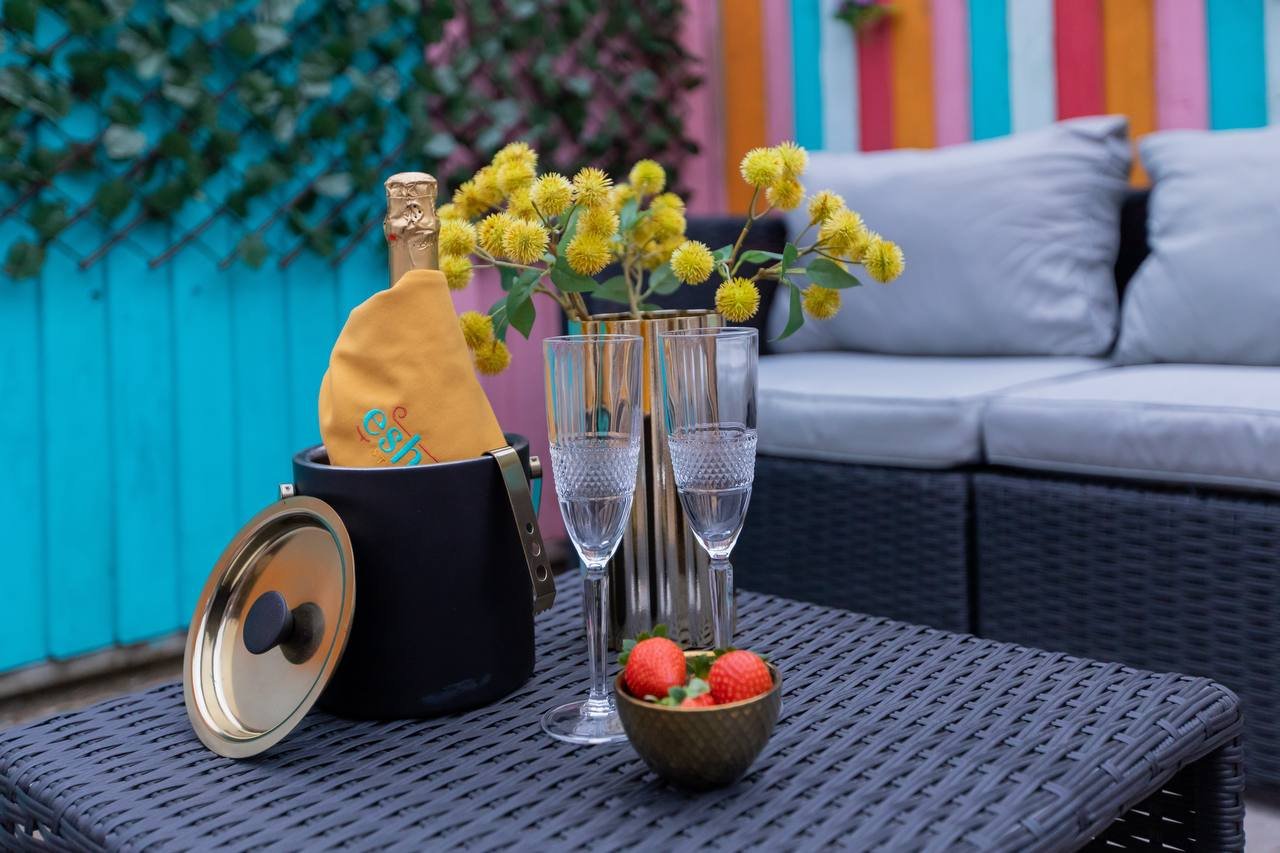 Outdoor patio table with yellow flowers, champagne glasses, fruit bowl and decorative items