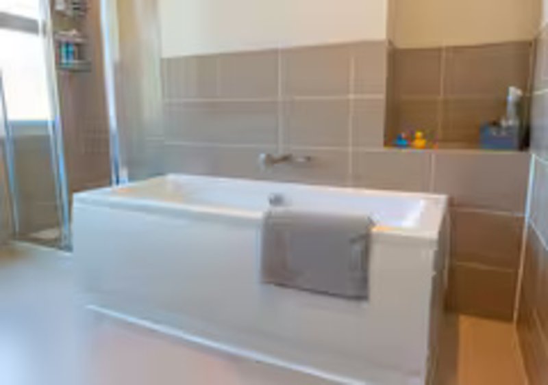 Modern bathroom with white freestanding bathtub, grey towel, and tiled walls