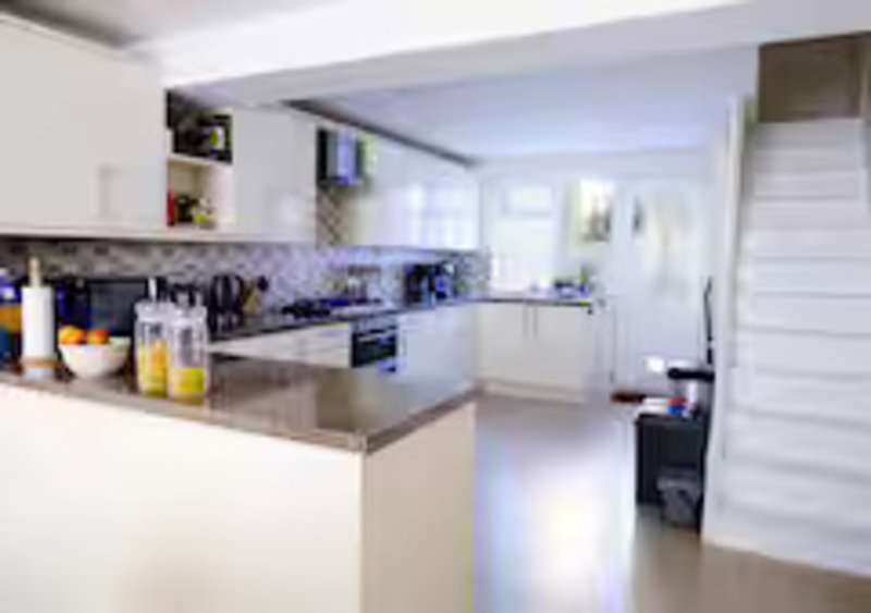 Modern kitchen with white cabinetry, island counter, stainless steel appliances and blue backsplash