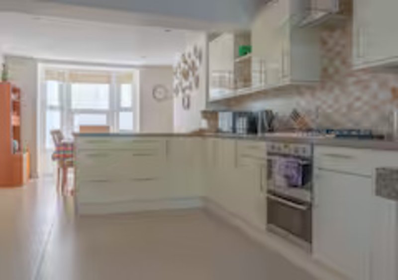 Modern kitchen with cream cabinets, stainless steel appliances, and window overlooking garden