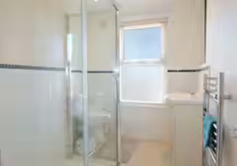 Modern bathroom with glass shower enclosure, window, and heated towel rail